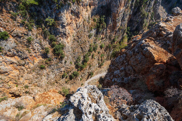 Narrow, steep, rocky valley from above, with small footpath at the bottom, in sunshine, Aradena gorge, Greece, island of Crete, wide angle lens
