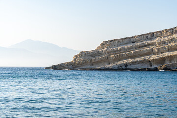 Stratified rock runs obliquely into the sea, clear blue sky, landscape, telephoto