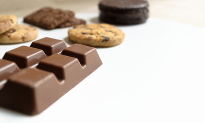 Barra de chocolate con galletas y alfajor argentino sobre mesa o superficie blanca. 