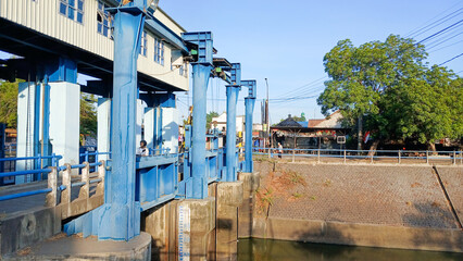 Tulungagung, Indonesia October 12, 2024: A blue metal dam with several gates, used to control the flow of river water. Located in Majan village, Kedungwaru District, Tulungagung Regency.