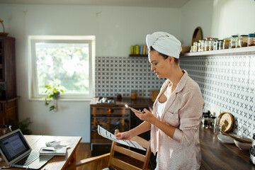 Serious woman working from home with laptop and bills in kitchen