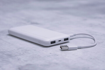 White power bank on a marble table. Portable charger for gadgets.