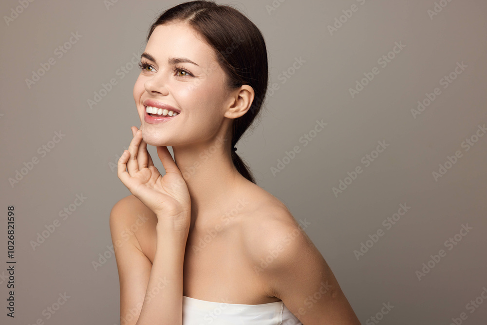 Wall mural Beautiful young woman smiling and looking at the camera with her hand on her chin