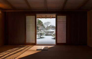 Open wooden doors reveal a snowy scene with a book resting on the wooden floor inside.