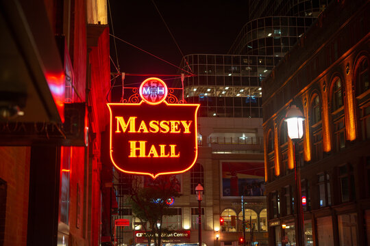 wider view of iconic neon sign outside historic Massey Hall, an event venue, pictured from Shuter Street in downtown Toronto, Canada at night