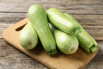 Board with fresh zucchinis on wooden table, closeup