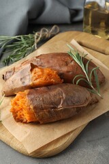 Tasty cooked sweet potatoes served with rosemary on grey table, closeup