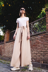 A young girl dressed in wide trousers and a hat walks through the old city.