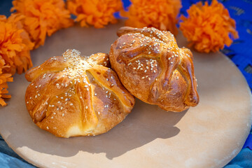 Two Pan de Muerto on a Clay Plate with Marigold Flowers Decorating the Corners