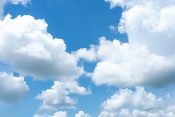 Fluffy white clouds drift across a bright blue sky, painting a beautiful summer day