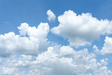 Beautiful fluffy white clouds drift across a clear blue sky, painting a breathtaking cloudscape
