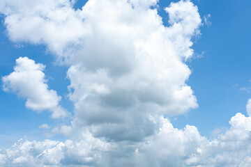 Fluffy cumulus clouds drift across a bright blue sky, painting a beautiful summer day