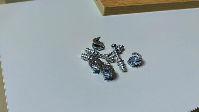 a man's hand puts a minifix screw into a collection of screws