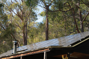 Rural cabin roof covered in photovoltaic PV solar panels generating off grid electricity energy