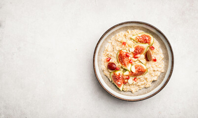 Oatmeal porridge with figs, nuts and pomegranate, top view, copy space