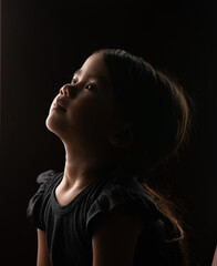 A captivating portrait of a young girl gazing thoughtfully upwards, deep in contemplation