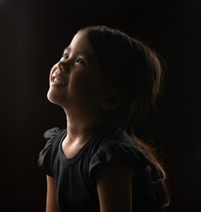 Obraz premium A delighted and joyful child gazes upwards, illuminated softly by gentle, warm lighting