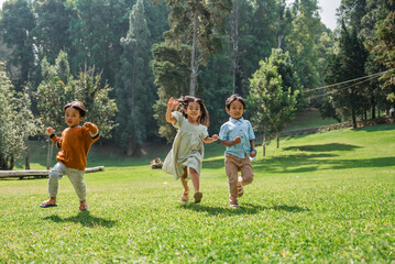 Obraz premium Children are playfully running around in a colorful and vibrant green park, enjoying life