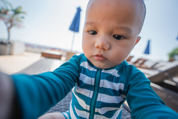 An adorable baby joyfully engaging with their surroundings while in a sunny pool area