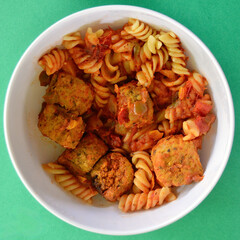 Italian style meatballs with pasta, tomato sauce and cheese in a bowl.