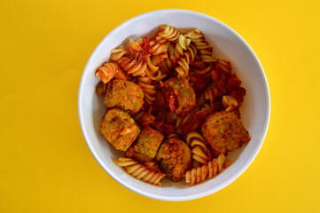 Italian style meatballs with pasta, tomato sauce and cheese in a bowl.