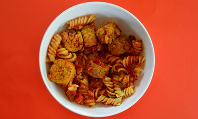Italian style meatballs with pasta, tomato sauce and cheese in a bowl.