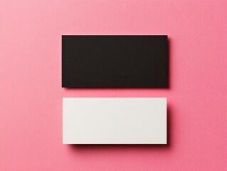 Fototapeta premium Two business cards, one black and one white, placed on a pink surface, emphasizing contrast and minimalistic design for branding.