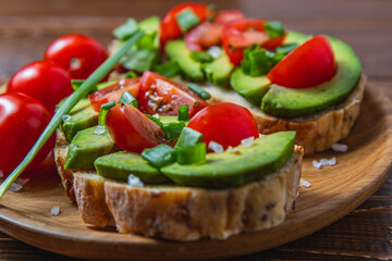 Avocado toast topped with tomato and green onion on a slice of carrot bread