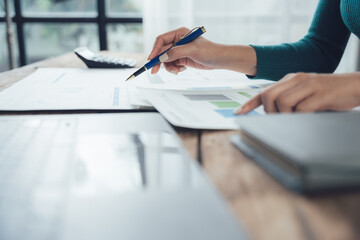 Focused Analysis: A close-up shot of a woman's hand meticulously reviewing financial documents, her...