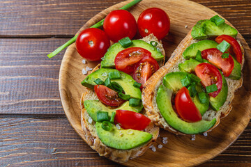 Avocado toast topped with tomato and green onion on a slice of carrot bread