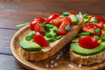 Avocado toast topped with tomato and green onion on a slice of carrot bread