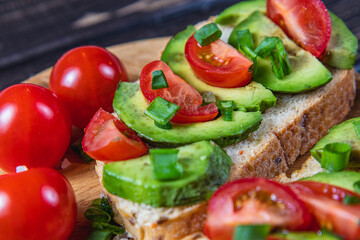 Avocado toast topped with tomato and green onion on a slice of carrot bread