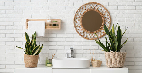 Interior of light bathroom with modern sink and wicker mirror