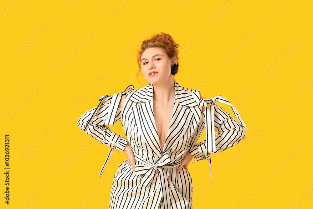 Wall mural Beautiful young woman in stylish striped dress on yellow background