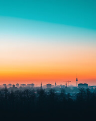 City skyline at dawn with vibrant colors and silhouettes of buildings.