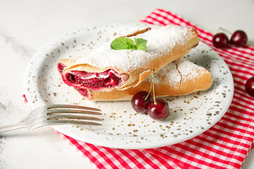Napkin and plate with tasty cherry strudel on marble background, closeup