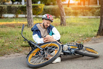 Young man with injured leg after falling off his bike outdoors