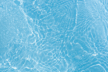 Blue water with ripples on the surface. Defocus blurred transparent blue colored clear calm water surface texture with splashes and bubbles. Water waves with shining pattern texture background.