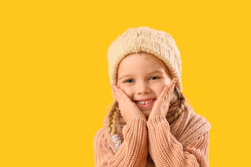 Cute little girl in winter clothes on yellow background, closeup