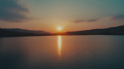 Fototapeta premium Peaceful Sunset Reflection on Serene Lake Surrounded by Rolling Hills