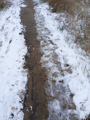 The first snow has fallen. A thin layer of white snow lies along the path. Late autumn, early winter. Background, space for text. Weather. Cold snap.