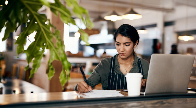 Cafe owner, laptop or writing on documents for coffee shop planning, financial tracking or profit accounting. Thinking, paperwork or technology for small business woman in restaurant for bakery sales