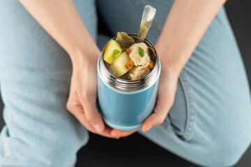 Food in a thermobox. Girl holds a thermos with food. Hot dish for the road. Food in a food thermos. View from above.