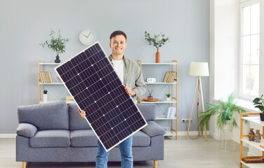 Portrait of a happy, smiling man holding a solar panel. Happy house owner uses a photovoltaic...