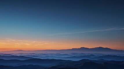 Obraz premium A breathtaking view of mountain ranges at sunset, with layers of blue hues and a warm orange sky. Silhouettes of mountains against a vibrant sunset sky