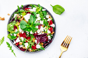 Beet and ricotta cheese salad with arugula, lettuce, chard and walnuts, white background