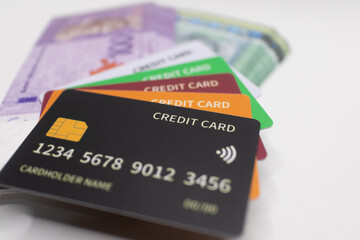 Black credit card placed on a stack of purple and green Malaysian Ringgit banknotes, symbolizing luxury, cashless transactions, and financial services .