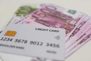 White credit card placed on a stack of purpleand greenEuro banknotes, symbolizing cashless payments, digital transactions, and European currency.