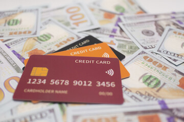 Maroon credit card lying on a spread of blue and gold US  bills, symbolizing luxury financial transactions, wealth management, and economic growth .