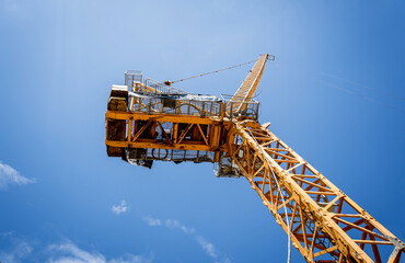 A large yellow crane stands out against a bright blue sky